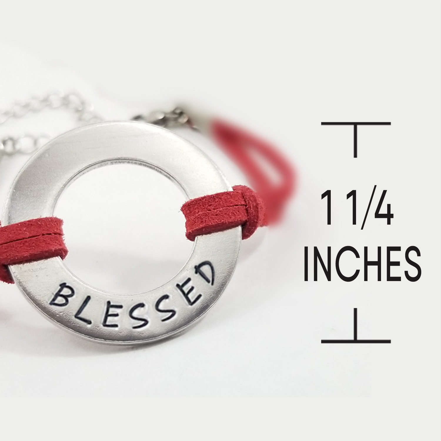 The Men Women Personalized Washer Bracelet features a silver circular pendant engraved with “BLESSED” on a red suede cord. The 1 1/4-inch pendant is displayed against a white background, with part of the chain visible behind it. Read more at Stamping Cat Studio (stampingcatstudio.com).