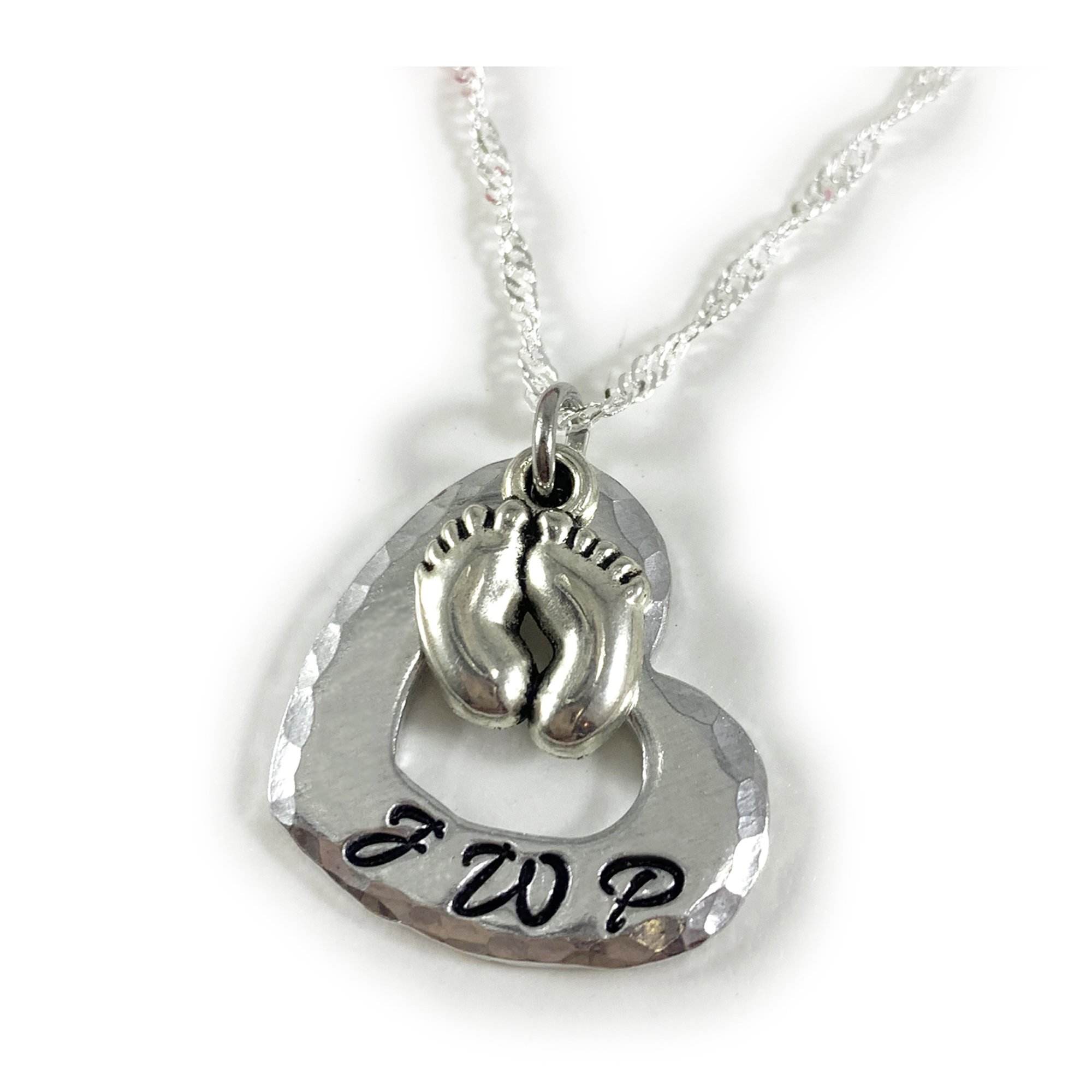 The Baby Feet and Heart Necklace features a hammered silver heart pendant with a central baby feet charm and "JWP" engraved in black at the bottom, all hanging from a delicate chain. Read more at Stamping Cat Studio (stampingcatstudio.com).