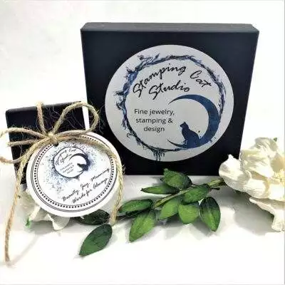A black box with a circular “Stamping Cat Studio” logo and the text “Fine jewelry, stamping & design” sits beside a twine-tied box. In front are the Rich Lapis Lazuli, Sterling Oval Necklace and Earrings. Read more at Stamping Cat Studio (stampingcatstudio.com).