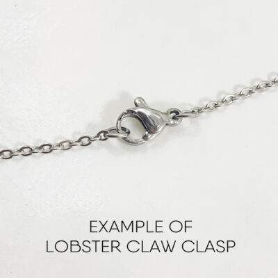 A close-up of the Dreamy Sun, Moon And Stars Necklace features an oval lobster claw clasp with a small lever in the center. Below the chain, “EXAMPLE OF LOBSTER CLAW CLASP” is written on a white background. Read more at Stamping Cat Studio (stampingcatstudio.com).