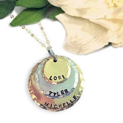 Kids Names Neck main new featuring three layered, hammered, circular metal charms stamped with the names “Lori,” “Tyler,” and “Michelle.” Read more at Stamping Cat Studio (stampingcatstudio.com).