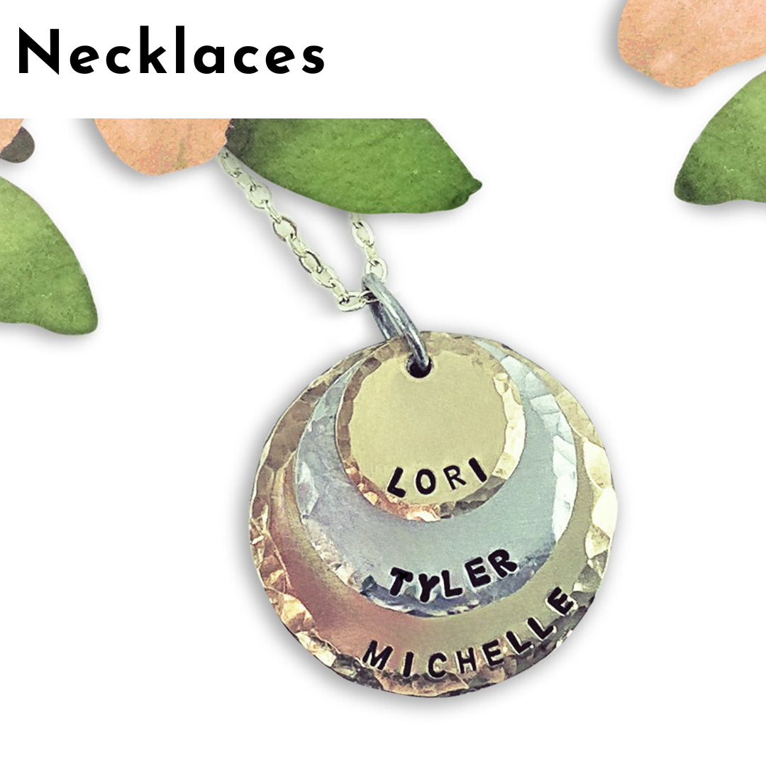A layered metal necklace pendant with three circular discs, each stamped with a name, creates a stunning piece of personalized jewelry. The pendant hangs from a silver chain, with leaves and the word "Necklaces" above. Read more at Stamping Cat Studio (stampingcatstudio.com).