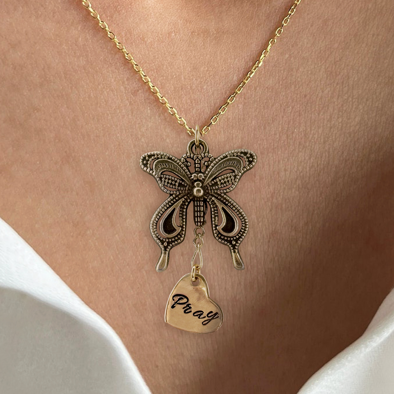 The Bronze Butterfly neck NL features a large ornate butterfly pendant and a small engraved heart-shaped charm, hanging around the neck and paired with a white off-shoulder outfit. Read more at Stamping Cat Studio (stampingcatstudio.com).