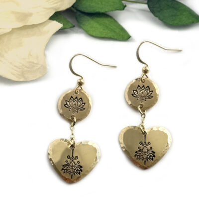 The Gold Lotus Heart Dangle Earrings main feature hammered round and heart-shaped discs with engraved lotus flowers, shown on a white background accented by a soft cream flower and green leaves in the corner. Read more at Stamping Cat Studio (stampingcatstudio.com).