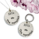 The Pers Graduation neck or key main features two round silver charms—one necklace, one key ring—engraved with "2026 The memories" and a graduation cap. Pink and purple faux flowers add a festive accent to this memorable graduation gift. Read more at Stamping Cat Studio (stampingcatstudio.com).