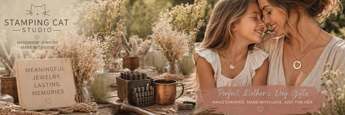 A mother and daughter smile outdoors, wearing stamped jewelry. Surrounded by flowers, a mug, and metal stamps, a sign reads MEANINGFUL JEWELRY. LASTING MEMORIES. Shop meaningful Mother’s Day gifts at Stamping Cat Studio. Read more at Stamping Cat Studio (stampingcatstudio.com).