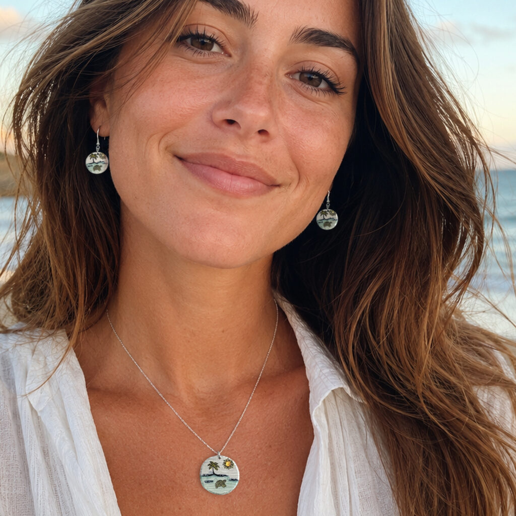 A smiling woman with long brown hair wears a white shirt and the Dreamy Beach NL set—silver round earrings and a matching beach scene pendant—while standing outdoors with the ocean and sky blurred in the background. Read more at Stamping Cat Studio (stampingcatstudio.com).