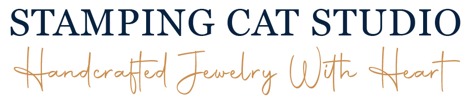 The New Logo NL words showcases the text “STAMPING CAT STUDIO” in bold navy uppercase letters above “Handcrafted Jewelry With Heart” in an elegant gold handwritten script, all set against a clean white background. Read more at Stamping Cat Studio (stampingcatstudio.com).